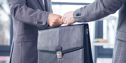 tradesecrets a close up of two men in business suits - one is passing a briefcase to the other